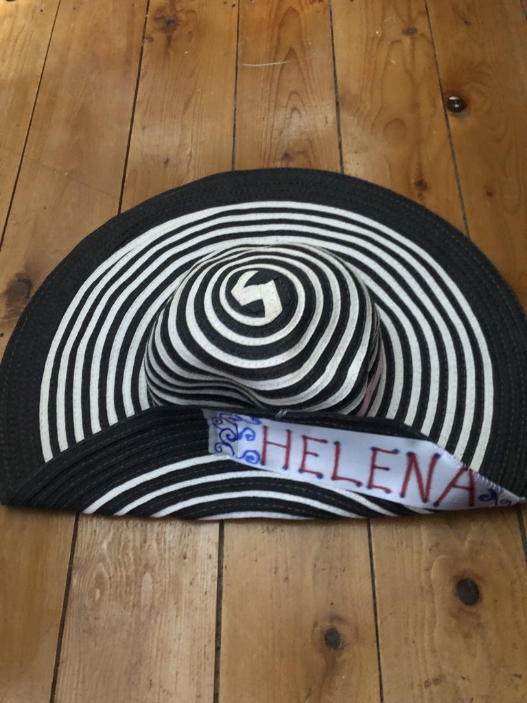 Black and white striped hat with a large brim. A label on the upturned brim says 'Helena'