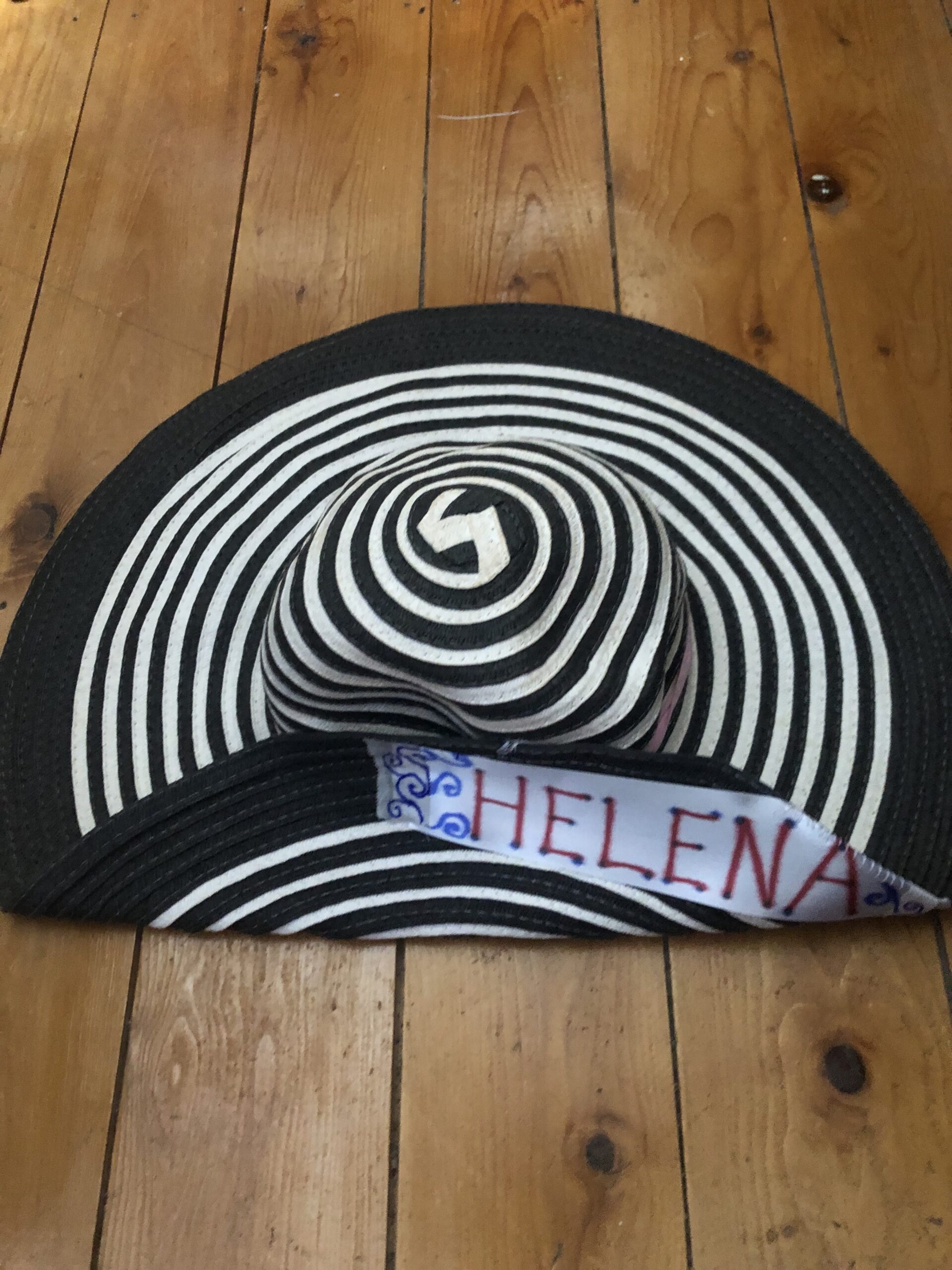 Black and white striped hat with a large brim. A label on the upturned brim says 'Helena'