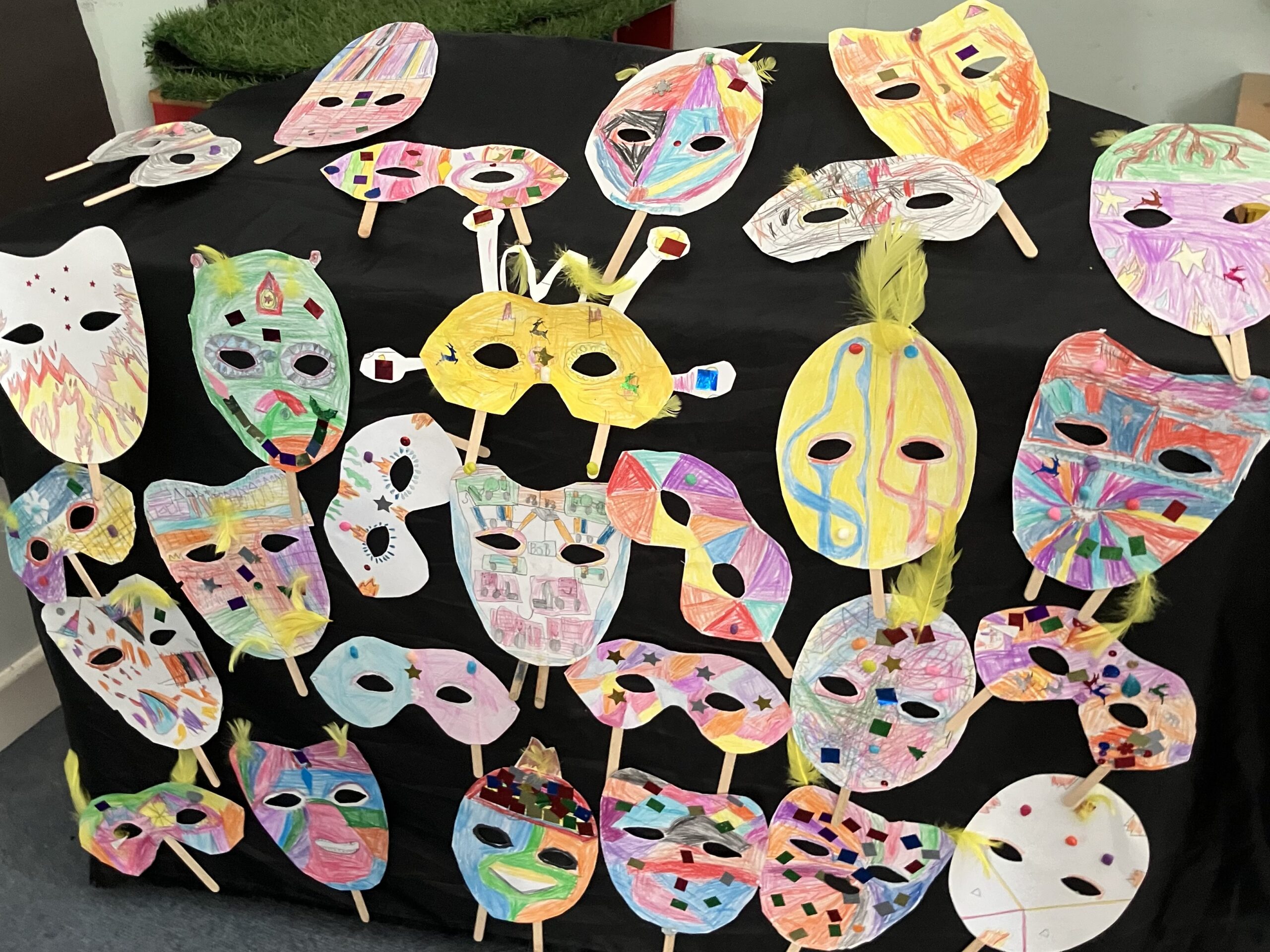 coloured masks made by Y1/2 at Barkston & Syston Primary School, displayed on black cloth.